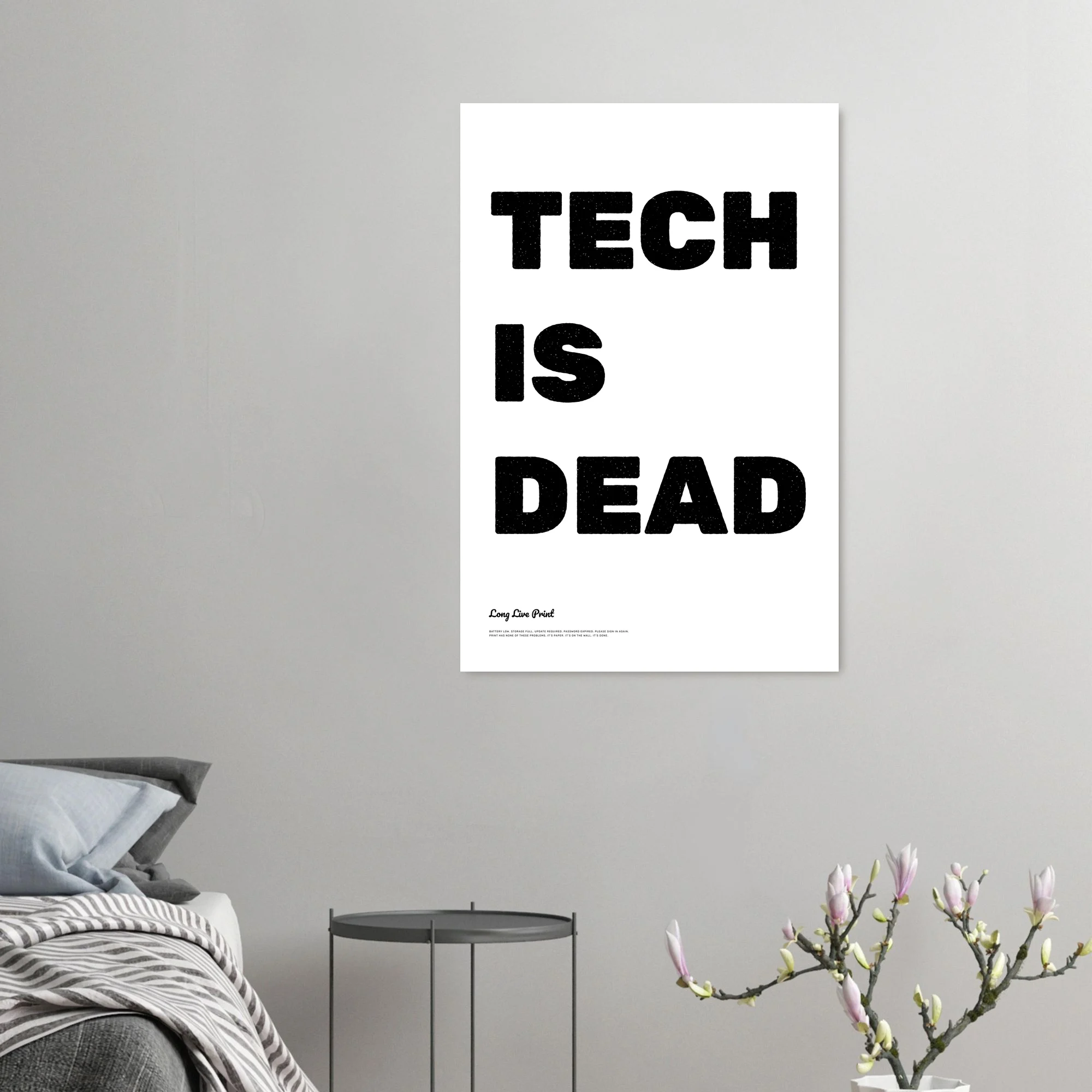The poster on a gray wall above a bedside table and a magnolia branch